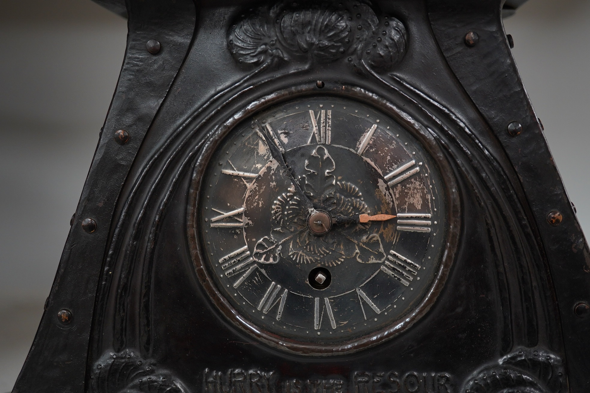 An Arts & Crafts embossed copper mantel timepiece, probably Glasgow School of Art, c.1900, with pewter dial, the text under the dial reads; ‘Hurry is the resource of the faithless’, 21.5cm high. Condition - fair, restora